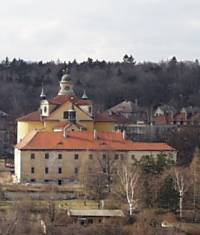 Před kostelem Nejsvětější trojice stojí klášter, pohled ze Slánské hory. 